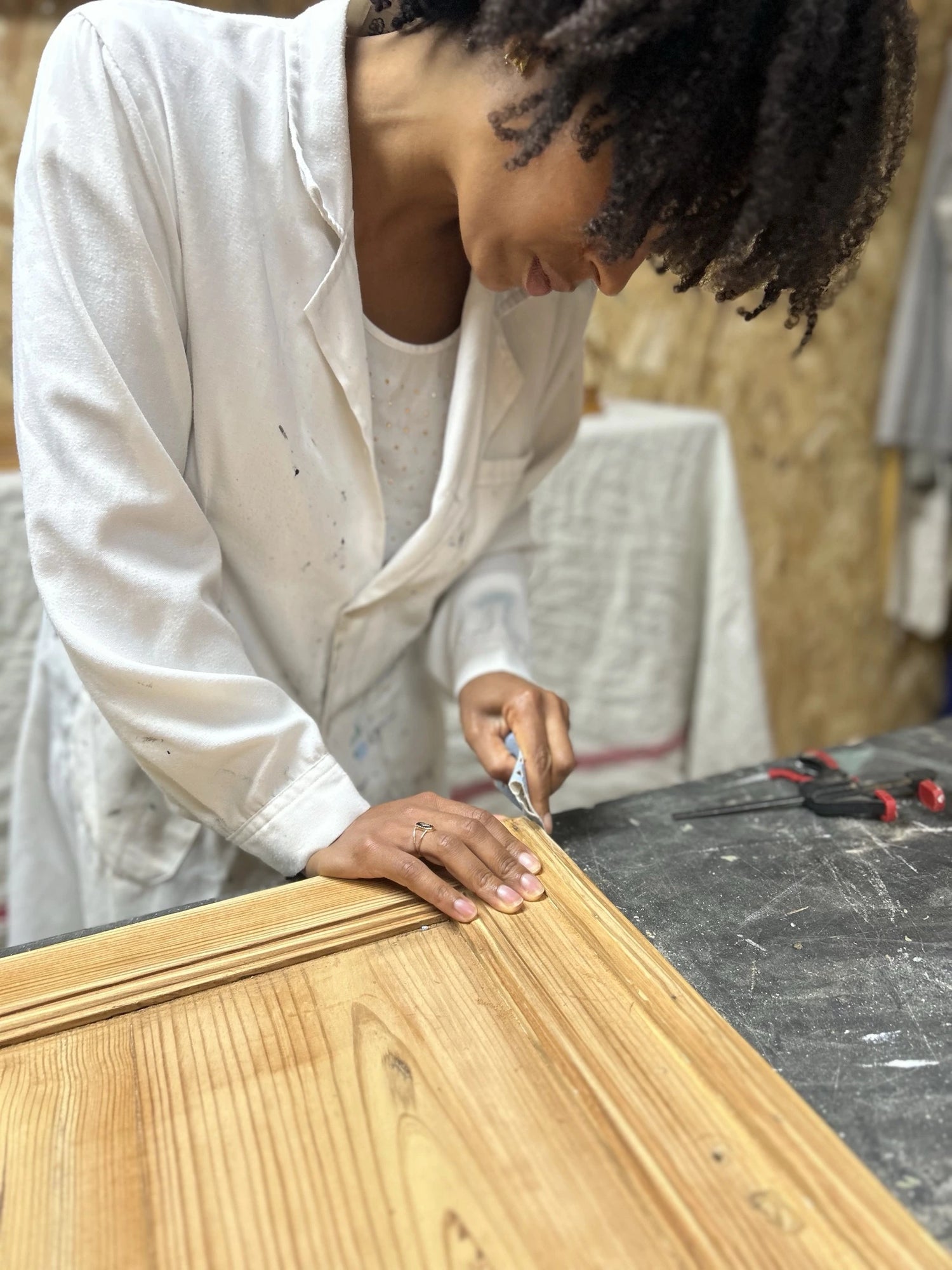 Femme en train de poncer un meuble en bois massif